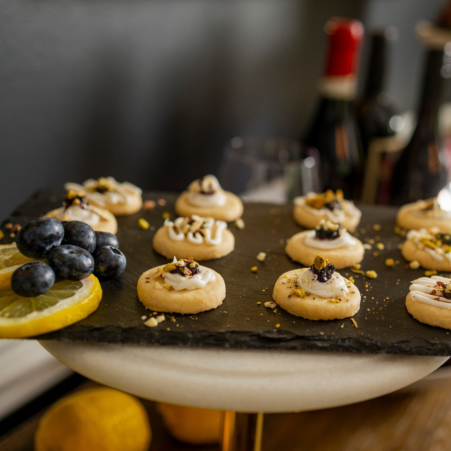 Small Lemon cookies on a slate platter with lemons and blueberries, blurred background