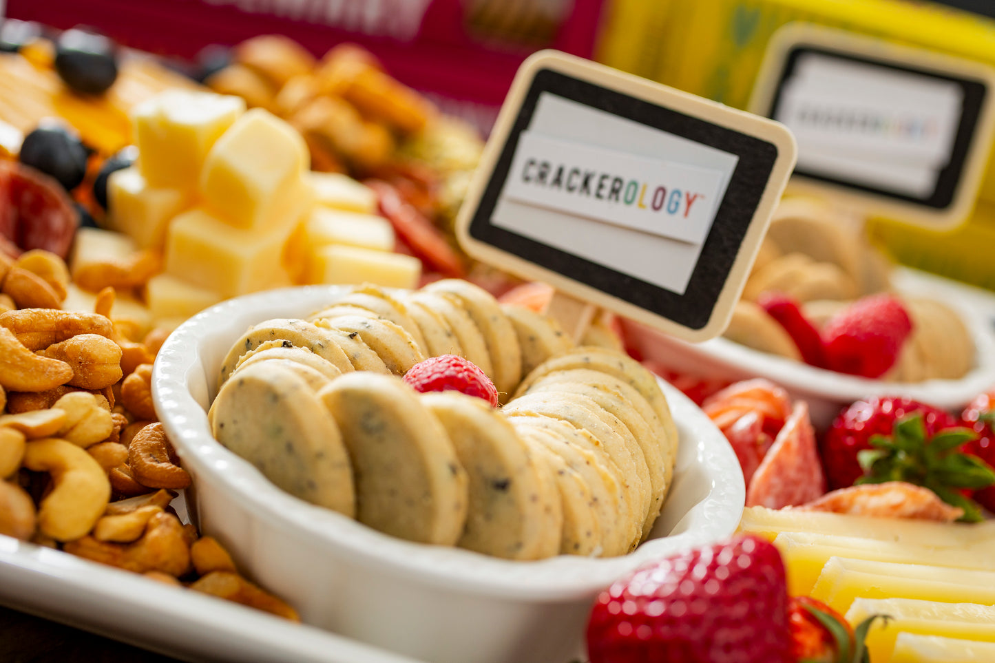 Assorted snacks including cookies, fruits, and nuts with a 'Crackerology' sign.
