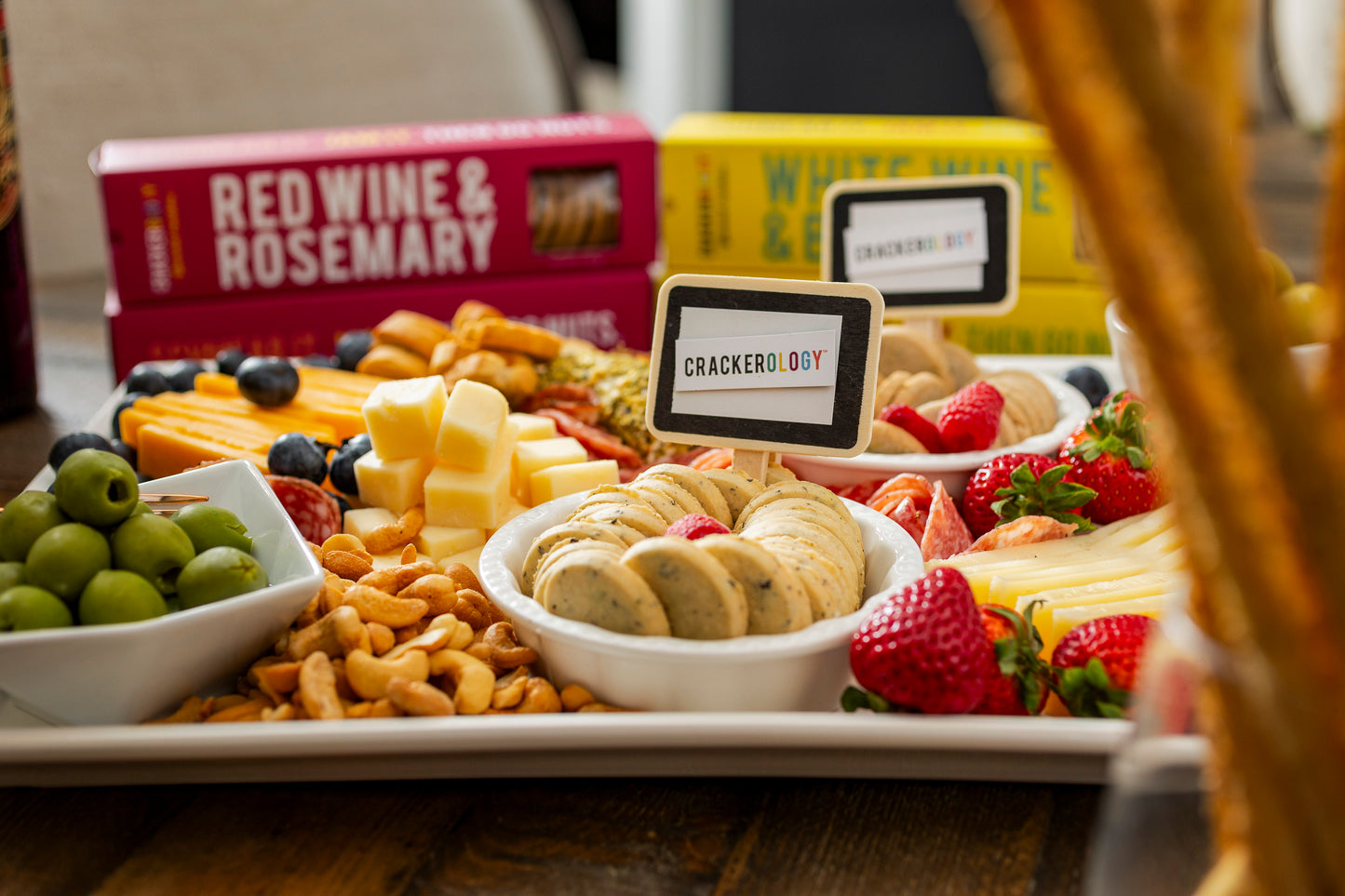 Assorted snack platter with crackers, fruits, and cheese on a table.