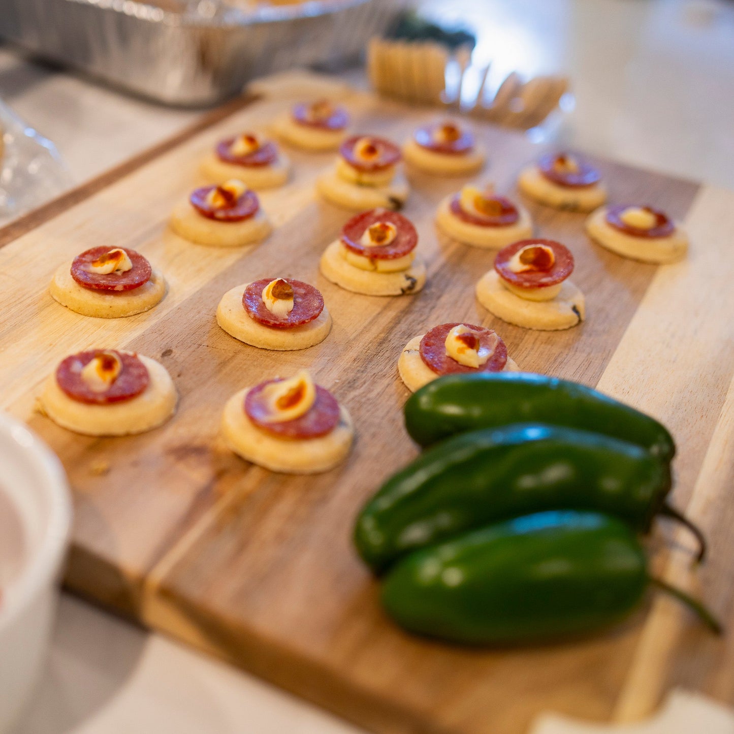 Small Crackerology appetizers on a wooden board with jalapenos.