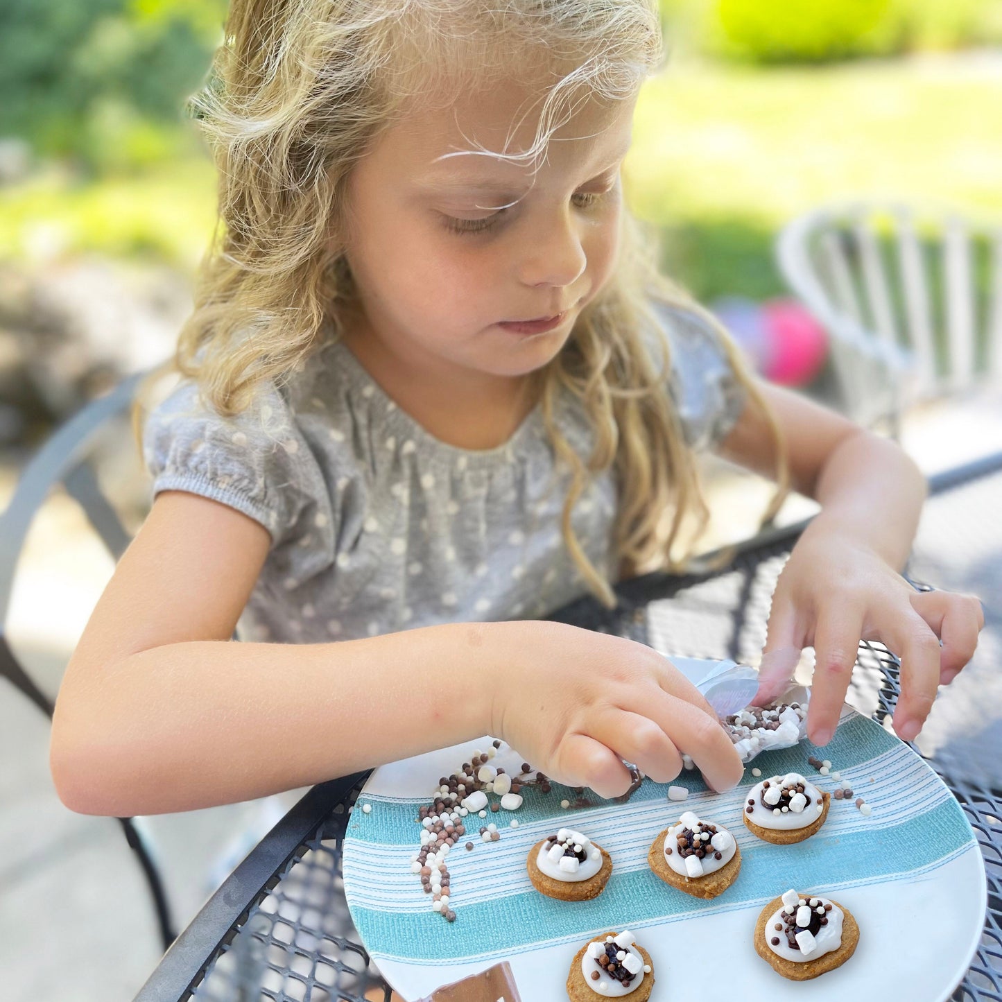 Young girl arranging cookies on a plate outdoors