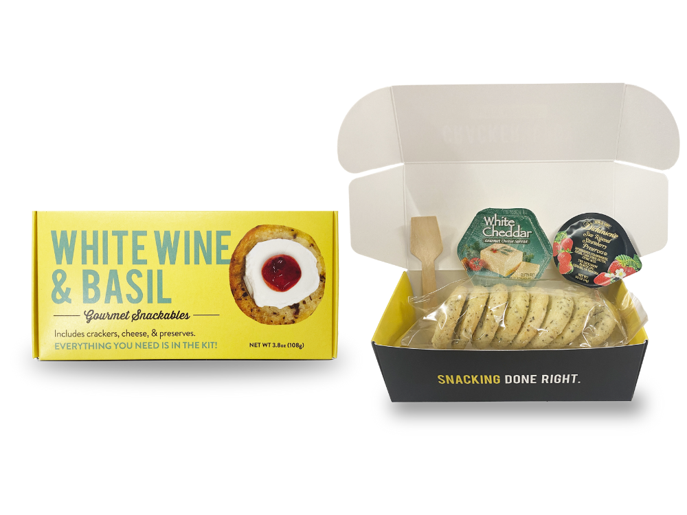 Packaging and contents of a snackable white wine and basil crackerology kit, including crackers, cheese, and jam.